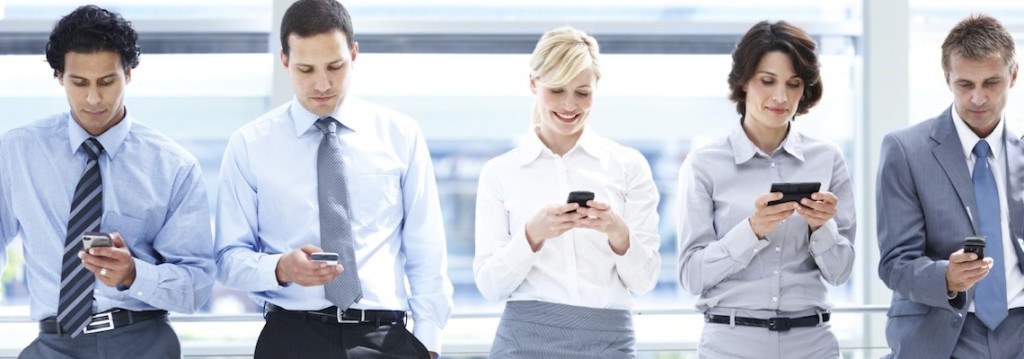 A group of executives standing in line and looking at their smartphones